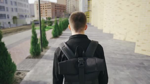 Young handsome pensive businessman walks in a modern urban area with a backpack - Video