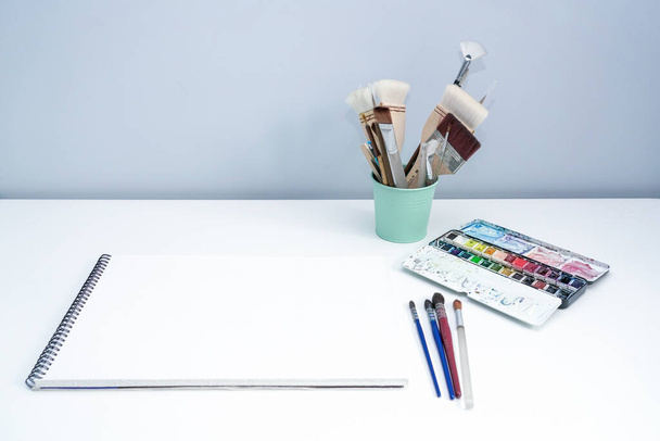 Tavolozza acquerello e pennelli da disegno su tavolo bianco. Acquerello strumenti di pittura casa sul desktop bianco
 - Foto, immagini
