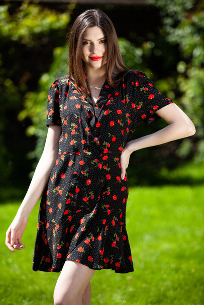 Красивая девушка Брюнетка позирует снаружи в черном с цветочным узором платье
.  - Фото, изображение