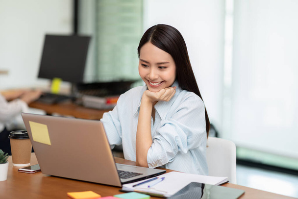 Happy Asian business woman patrząc laptop pracy i uśmiech w nowoczesnym biurze lub Co-Working Space, Business Startup Concept - Zdjęcie, obraz