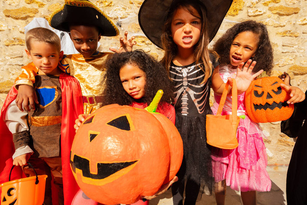 Group of cute little kids in costume with girl hold huge orange pumpkin Halloween - Photo, Image