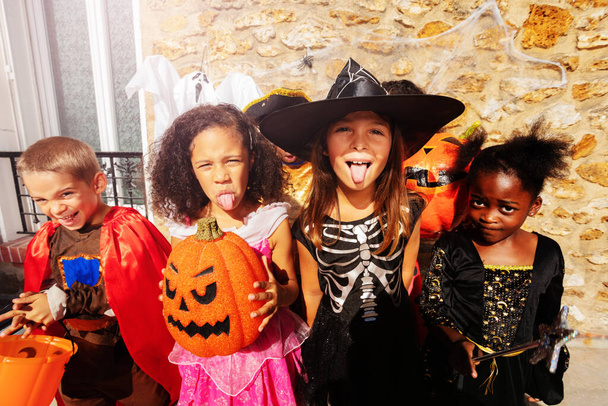 Close portrait of the girl over large group of children boys and girls in Halloween costumes stand together showing spooky gestures looking on camera - Photo, Image