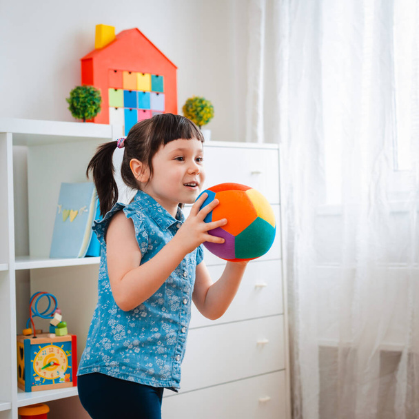 children little girl play in a children's game room, throwing ball. concept of interaction parent and kid, communication, mutual play, quarantine, self-isolation home, education. - Photo, Image