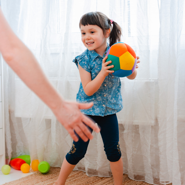 παιδιά κοριτσάκι παίζουν σε ένα παιδικό δωμάτιο παιχνιδιού, ρίχνοντας μπάλα. έννοια της αλληλεπίδρασης γονέα και παιδιού - Φωτογραφία, εικόνα