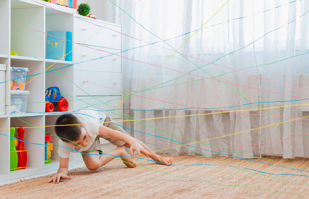 boy brother, siblings, friendschild climbs through a rope web, a game obstacle quest indoors. - Photo, Image