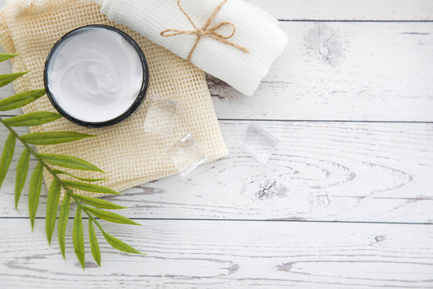 Spa beauty cosmetics on white marble table from above . Copy space. Flat layout. a jar of cream, leaves, flowers and a towel on a wooden background - Foto, afbeelding
