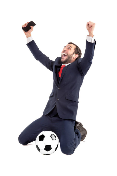 Empresario con pelota de fútbol y teléfono, celebrando aislado en blanco
 - Foto, imagen