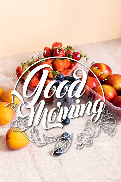 bosbessen, aardbeien, nectarines en perziken in plastic recipiënten bij goede morgen belettering op beige - Foto, afbeelding