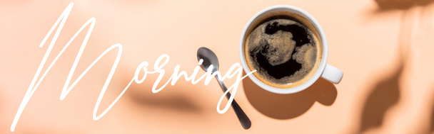 top view of coffee cup and teaspoon on beige with morning lettering, website header - Photo, Image