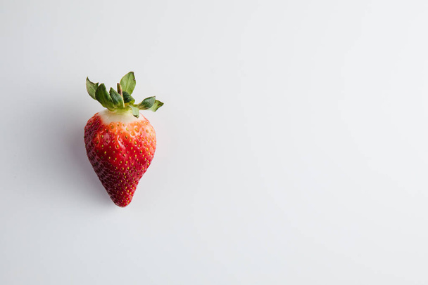 Großaufnahme einer Erdbeere auf einem weißen Tisch. Frische Beeren - Foto, Bild