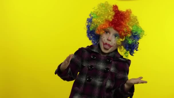 Malá holčička klaun v barevné paruce dělat hloupé obličeje, blbnout kolem, usmívat se, tančit. Halloween - Záběry, video