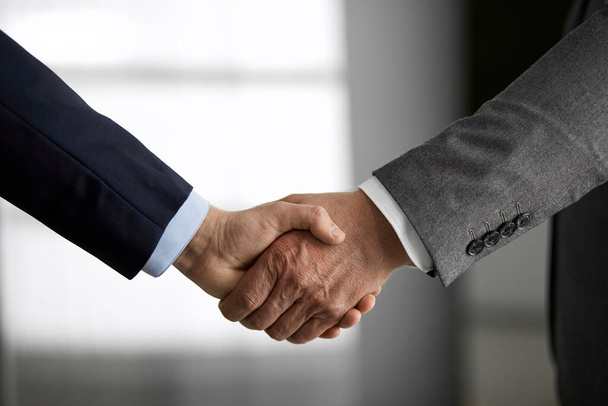 Business people in office suits standing and shaking hands, close-up. Business communication concept. Handshake and marketing - Fotografie, Obrázek