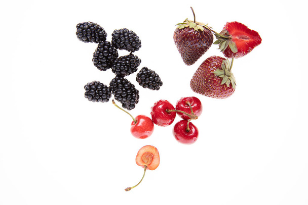 červené syrové čerstvé jahody a třešně s ostružinami na bílém pozadí, zblízka  - Fotografie, Obrázek