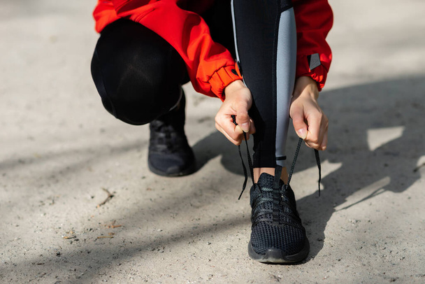 chica joven atando cordones de zapatos antes de correr en un sendero del bosque de verano de cerca - Foto, Imagen
