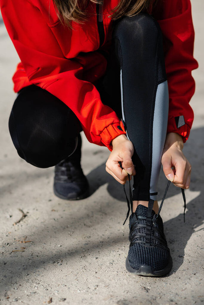 chica joven atando cordones de zapatos antes de correr en un sendero del bosque de verano de cerca - Foto, Imagen