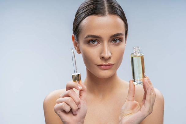 Young woman looking after skin with serum - Foto, Bild