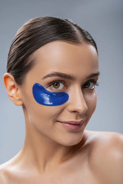 Smiling young woman with anti age mask under eyes - Photo, image