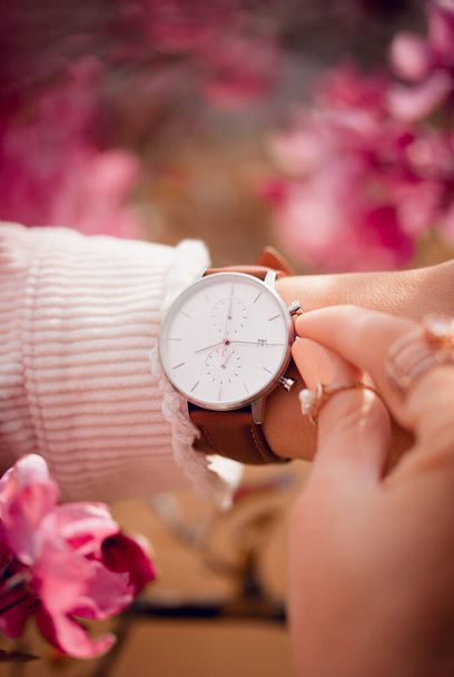 Stylish white watch on woman hand in flowers - Foto, afbeelding