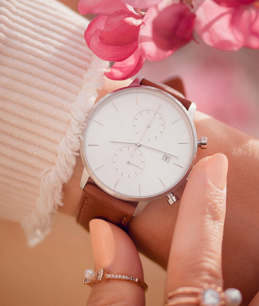 Stylish white watch on woman hand in flowers - Fotoğraf, Görsel