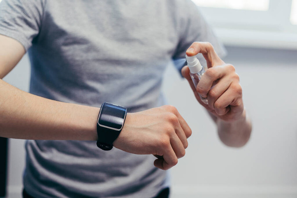 casual man spraying disinfecting his smart watch. - 写真・画像