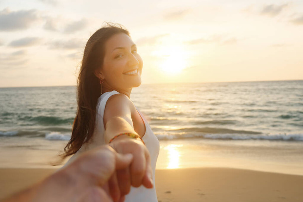 glimlachende vrouw loopt houden vriendje hand langs oceaan kust - Foto, afbeelding