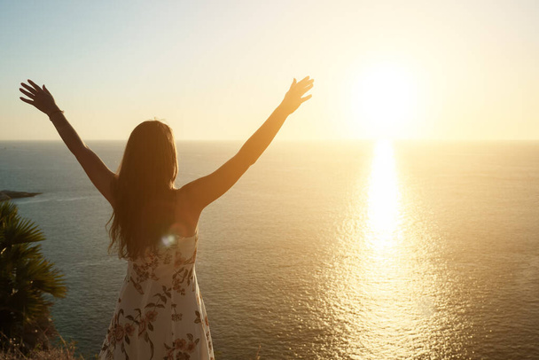 nainen kesällä mekko nostaa kädet rannalla auringonlaskun aikaan - Valokuva, kuva