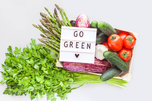 Φρέσκα βιολογικά λαχανικά σε οικολογικό ξύλινο κουτί με κείμενο Go Green lightbox flat lay, top view on gray background. Βιώσιμος τρόπος ζωής Μηδέν απόβλητα, πλαστική ελεύθερη έννοια - Φωτογραφία, εικόνα