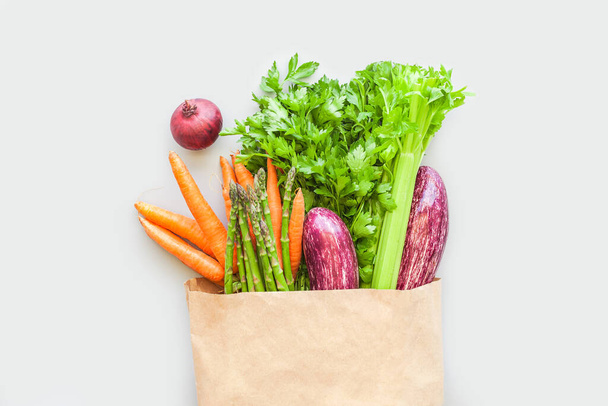 Fresh organic vegetables in eco craft paper shopping bag  in flat lay, top view with copy space on gray background. Sustainable lifestyle. Zero waste, plastic free, care package, donation concept - Fotó, kép