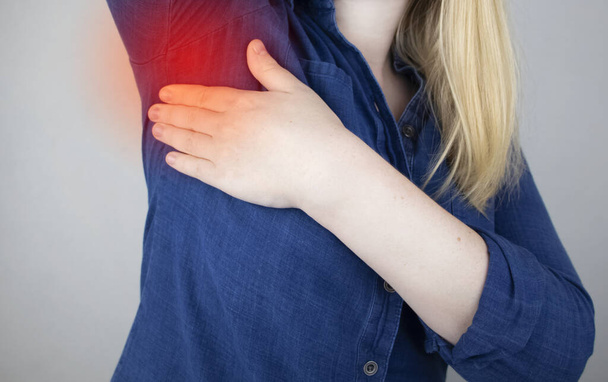 Eine Frau leidet unter Schmerzen in der Achselhöhle. Schweißausbrüche, unangenehmer Geruch, Rötungen, Zähne und Entzündungen in der Achselhöhle. Brustkrebs-Präventionskonzept - Foto, Bild