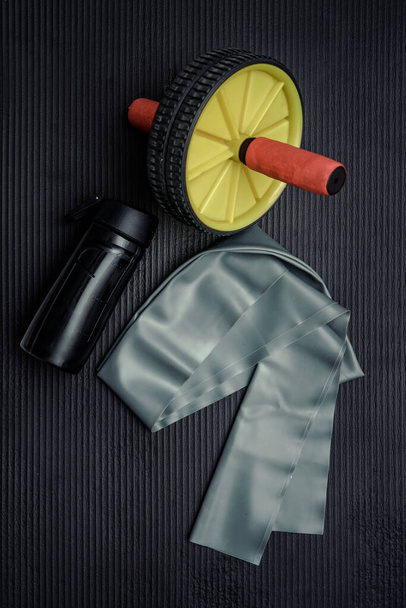 Home fitness yoga mat and abdominal wheel. Yoga mats and abdominal wheels in the gym. - Foto, imagen