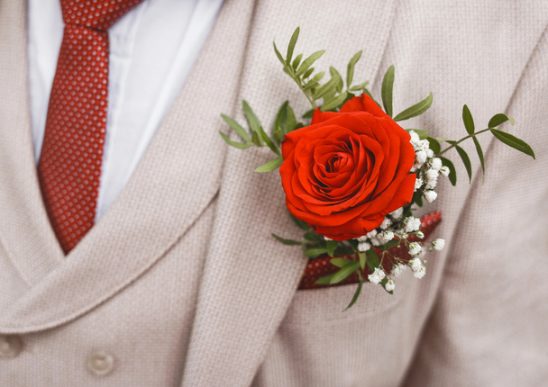 Beiger Hochzeitsanzug für Männer mit weißem Hemd und roter Polka-Dot-Krawatte, verziert mit einer Rosenblume, Nahaufnahme - Foto, Bild