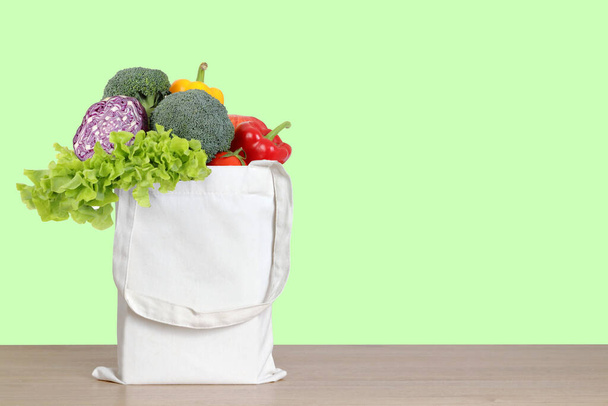 Bio-Gemüse in einem weißen Stoffbeutel auf einem Holzboden. Gesundes Essen, die Welt lieben, Plastikmüll reduzieren. Schneideweg. Kopierraum - Foto, Bild