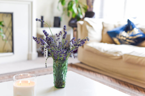 Interior moderno da casa da sala de estar com velas perfumadas e flores de lavanda na mesa de café
 - Foto, Imagem