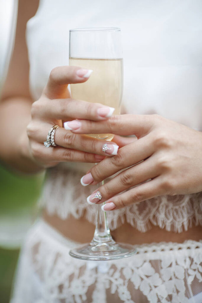 wedding and engagment ring on hand with champagne. woman's hand with glass of sparkling wine. High quality photo - Foto, afbeelding