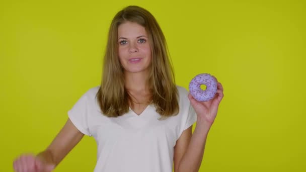 Mulher levanta a mão com um donuts azul, mostra aversão, aperta a mão e grimaces
 - Filmagem, Vídeo
