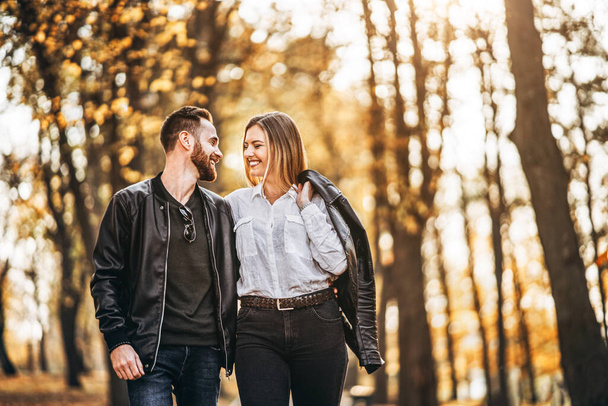 Portrait of a happy loving couple walking outdoor in the autumn park. Man and woman holding hands and smilling. - Fotografie, Obrázek