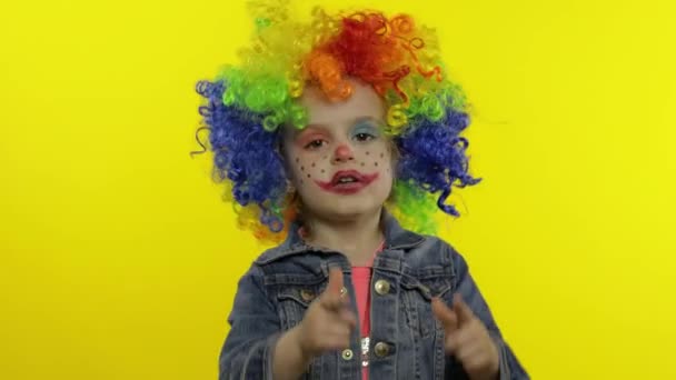Kleines Kindermädchen Clown in Regenbogenperücke macht dumme Gesichter. Spaß haben, lächeln, tanzen. Halloween - Filmmaterial, Video