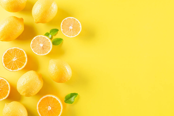 Yaz kompozisyonu portakallar, limon ve yeşil yapraklar ve pastel sarısı arka plan. Meyve asgari konsept. Düz konum, üst görünüm, kopyalama alanı. - Fotoğraf, Görsel