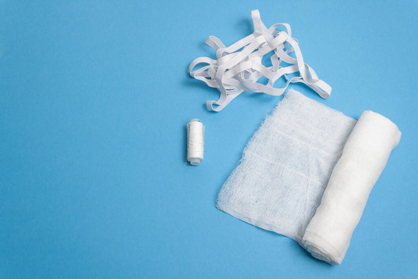 Gauze bandage, threads, rubber on blue background - Foto, afbeelding