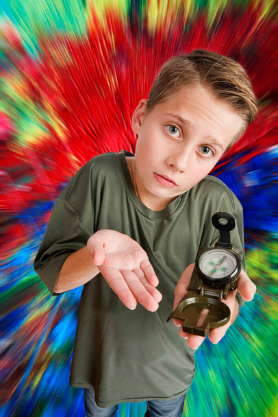 Imagem de um rapaz caucasiano de 12 anos numa vista elevada de três quartos de ângulo largo com uma bússola na mão esquerda, a olhar para a câmara impotente contra um fundo colorido e distorcido radialmente
. - Foto, Imagem