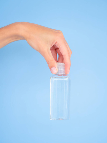 pot met heldere vloeibare mockup. Vrouwelijke hand met lege kleine 200ml transparante fles met heldere vloeistof. Kopieer ruimte op een fles - Foto, afbeelding