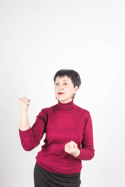 Photo of angry woman frowns face, shows fist, has dissatisfied facial expression, wears casual red clothes, threats about something, isolated over white background - Photo, Image