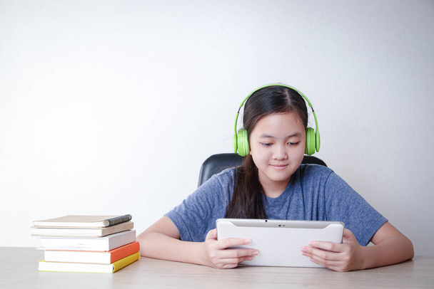Asiatische Mädchen lernen online von zu Hause aus durch die Videotelefonie-Anwendung auf ihrem Tablet. Konzept der sozialen Distanz, der Einsatz von Technologie für die Bildung. Kopierraum - Foto, Bild