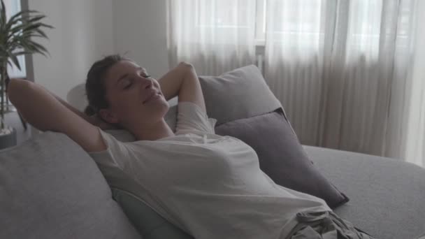 Happy relaxed woman lying on the sofa at home - Footage, Video
