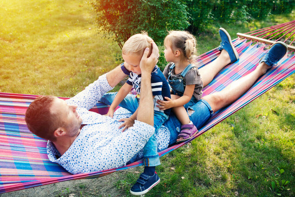 Young father with two kids having fun in hammock. Father's day, family day, children's day concept - Foto, Imagem