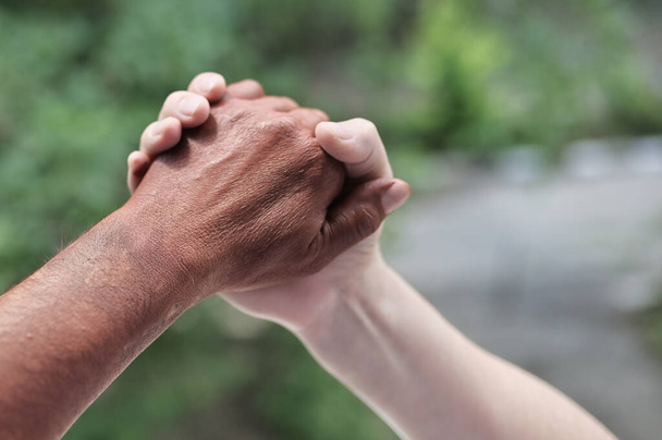 Чорні і білі руки тримають один одного в природі
 - Фото, зображення