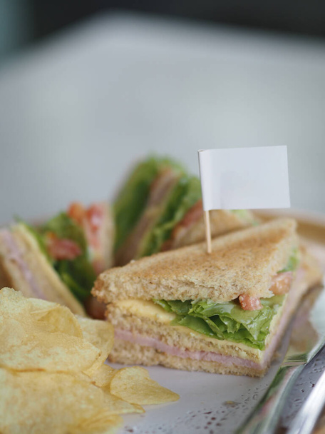 Ontbijt Sandwich Howe brood gevuld met ham en sla Salade groente Aardappel Chips, witte vlag stok op voedsel - Foto, afbeelding