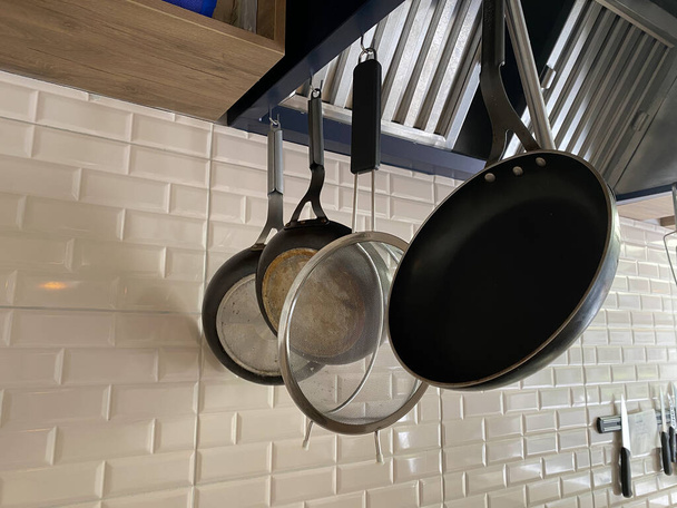 conjuntos de utensílios de cozinha pendurados na parede de polimento de concreto bruto para todos os usos na cozinha
 - Foto, Imagem