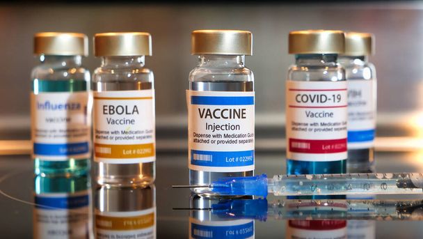 ワクチンのボトルcovid-19 、エボラ、ワクチン。エボラ、 covid-19 、インフルエンザ。黒のテーブルとステンレス製の背景に注射器を持つボトル. - 写真・画像