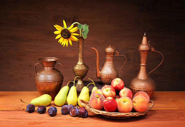 Miedziane naczynia, gruszki, śliwki i brzoskwinie na stole - Zdjęcie, obraz